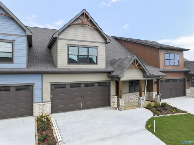 craftsman house with brick siding, driveway, an attached garage, and roof with shingles