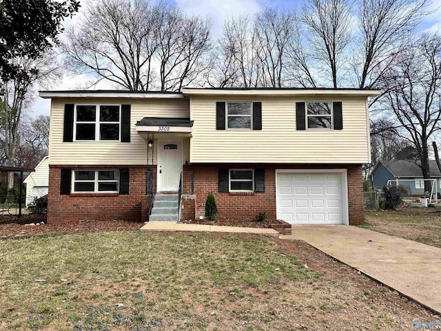 bi-level home featuring a front yard, brick siding, concrete driveway, and an attached garage