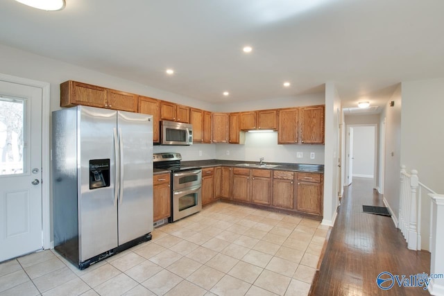 kitchen with dark countertops, recessed lighting, brown cabinets, and appliances with stainless steel finishes