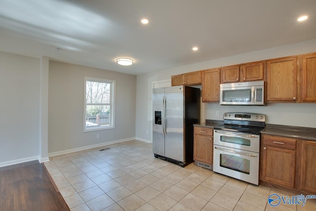 kitchen with dark countertops, visible vents, brown cabinets, and stainless steel appliances