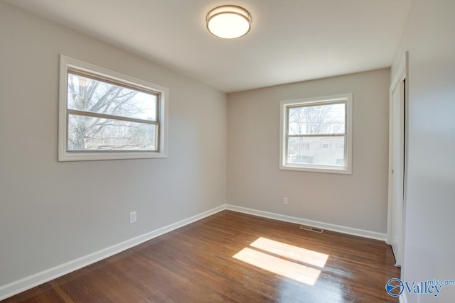 unfurnished bedroom with dark wood finished floors, multiple windows, and baseboards