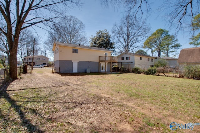 rear view of property with a lawn, a wooden deck, and fence