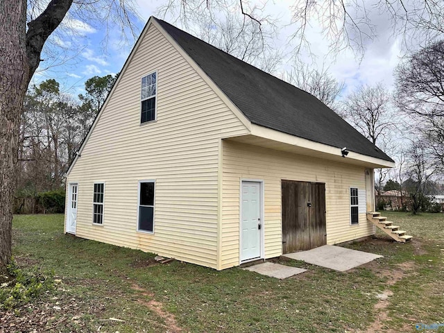 exterior space featuring a lawn and a shingled roof