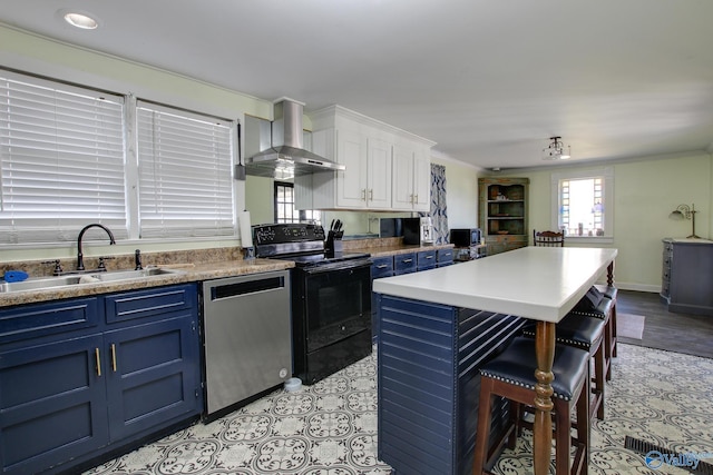 kitchen featuring blue cabinets, sink, electric range, stainless steel dishwasher, and wall chimney range hood