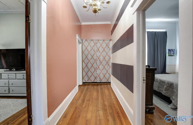 hallway with ornamental molding, wood-type flooring, and a chandelier