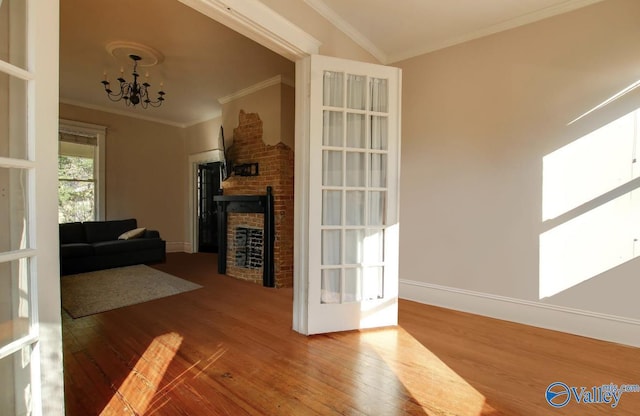 living room featuring wood-type flooring, crown molding, a chandelier, and a fireplace