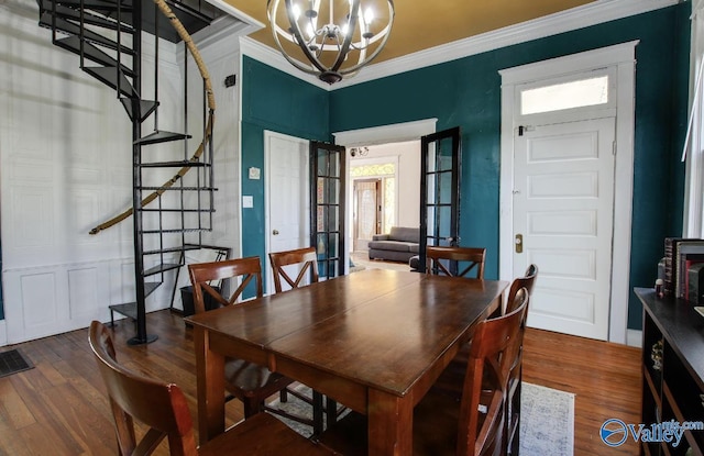 dining area with an inviting chandelier, ornamental molding, and wood-type flooring