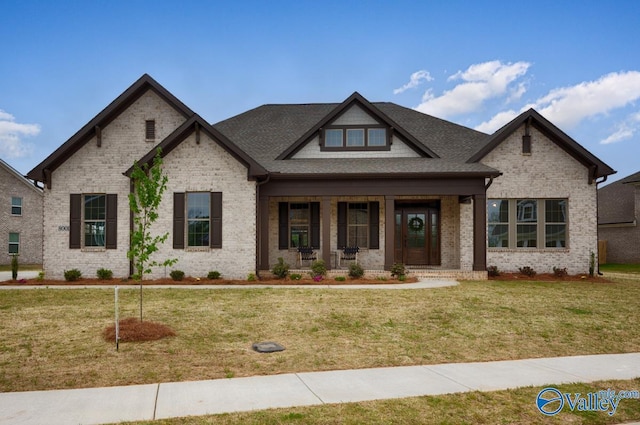 view of front facade with a porch, a front yard, and brick siding