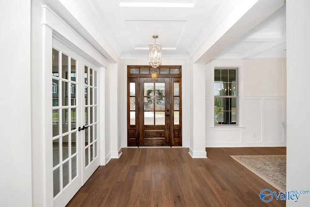 foyer entrance with a chandelier, dark wood-type flooring, french doors, and a decorative wall