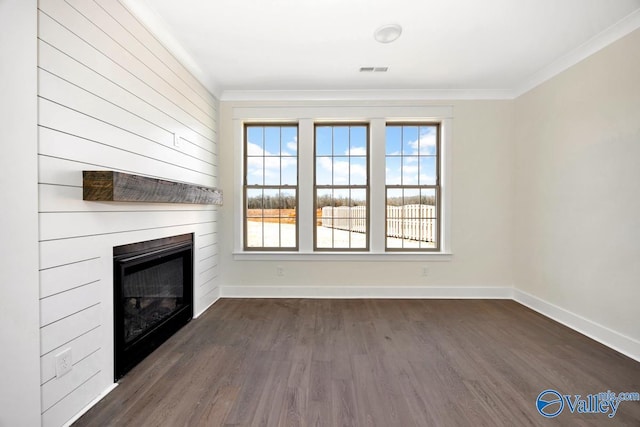 unfurnished living room with dark wood-style flooring, a glass covered fireplace, ornamental molding, and baseboards