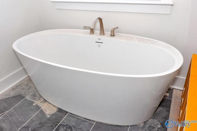 full bathroom with a soaking tub, baseboards, and marble look tile flooring