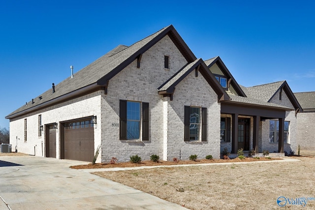 view of front of house with a garage, concrete driveway, brick siding, and central AC