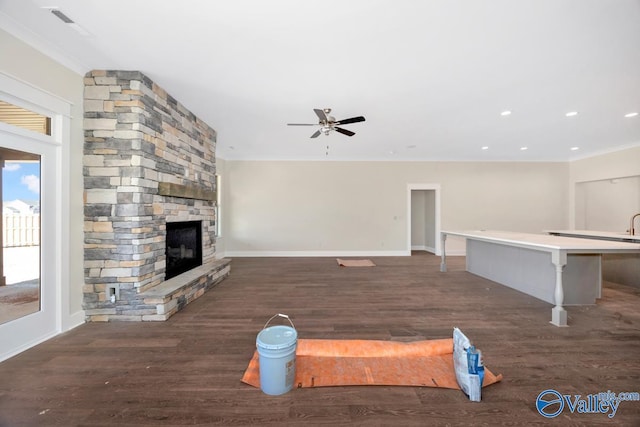 unfurnished living room with ceiling fan, baseboards, a fireplace, wood finished floors, and crown molding