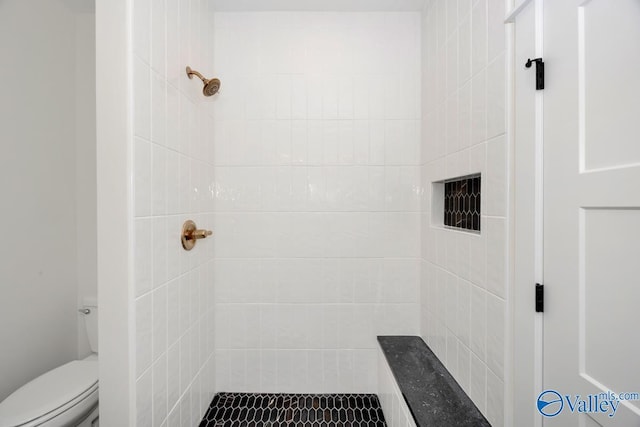 bathroom featuring a tile shower and toilet