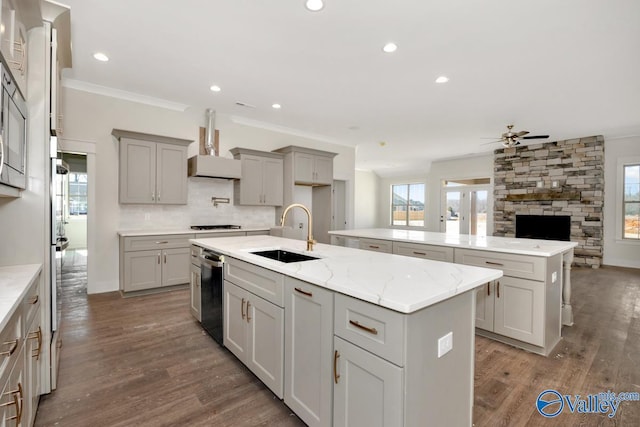kitchen featuring a sink, wall chimney exhaust hood, a center island with sink, gray cabinetry, and recessed lighting