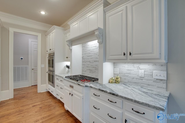 kitchen featuring crown molding, light hardwood / wood-style flooring, white cabinets, backsplash, and stainless steel appliances