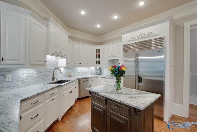 kitchen featuring sink, white cabinetry, ornamental molding, appliances with stainless steel finishes, and a kitchen island