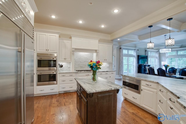 kitchen featuring tasteful backsplash, built in appliances, white cabinets, a kitchen island, and light hardwood / wood-style flooring