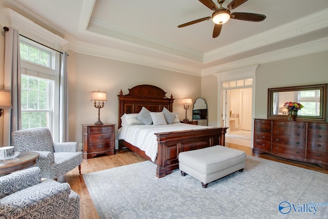 bedroom with ensuite bathroom, ceiling fan, a tray ceiling, crown molding, and light hardwood / wood-style flooring