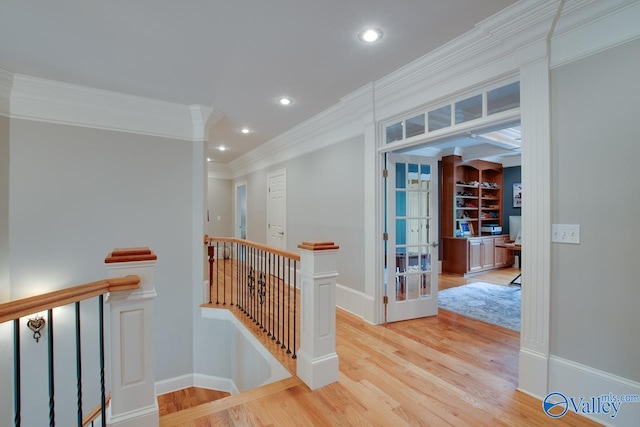 corridor featuring light hardwood / wood-style floors, built in shelves, and crown molding