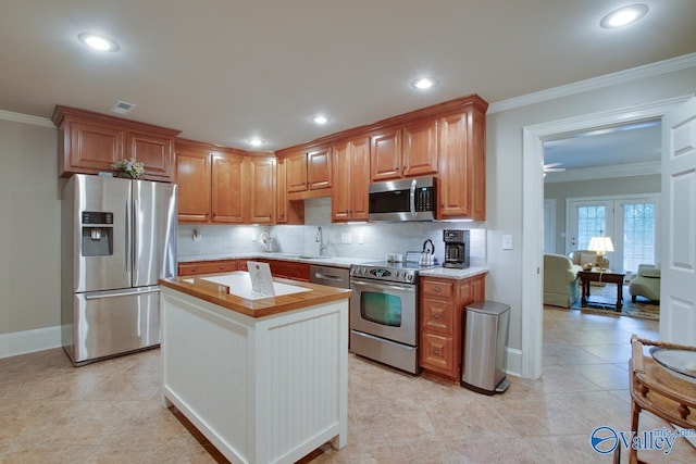 kitchen featuring ornamental molding, appliances with stainless steel finishes, a center island, and backsplash