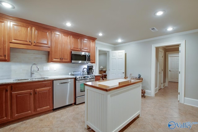 kitchen featuring sink, tasteful backsplash, crown molding, a kitchen island, and stainless steel appliances