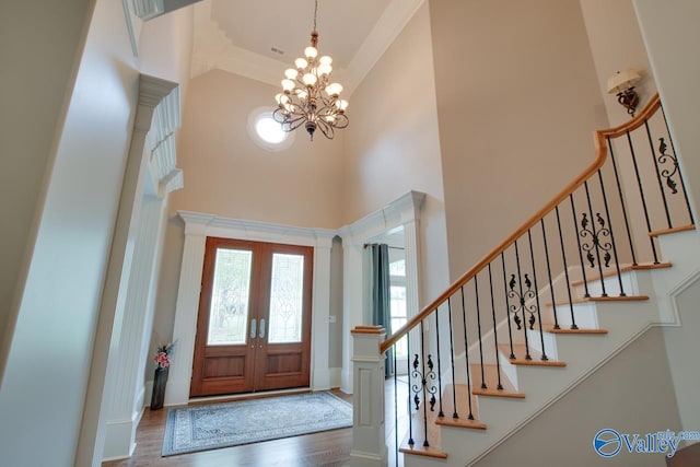 foyer featuring french doors, an inviting chandelier, a high ceiling, hardwood / wood-style flooring, and ornamental molding