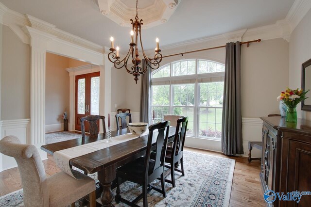 dining area with an inviting chandelier, hardwood / wood-style flooring, a raised ceiling, and crown molding