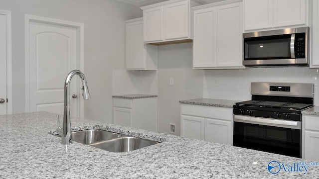 22392 Westminster Dr, Athens, AL 35613 - kitchen featuring stainless steel appliances, a sink, white cabinetry, light stone counters, and tasteful backsplash