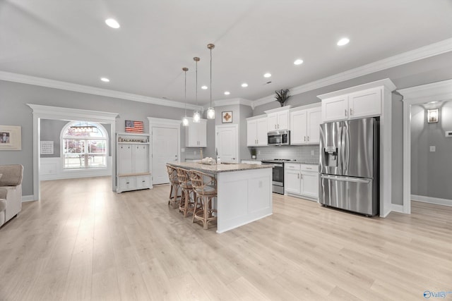 17067 Stonegate Dr, Athens, AL 35613 - kitchen with white cabinets, backsplash, a breakfast bar, a kitchen island with sink, and appliances with stainless steel finishes