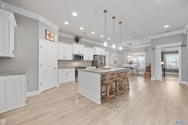 17067 Stonegate Dr, Athens, AL 35613 - kitchen featuring appliances with stainless steel finishes, a center island with sink, white cabinets, ornamental molding, and recessed lighting