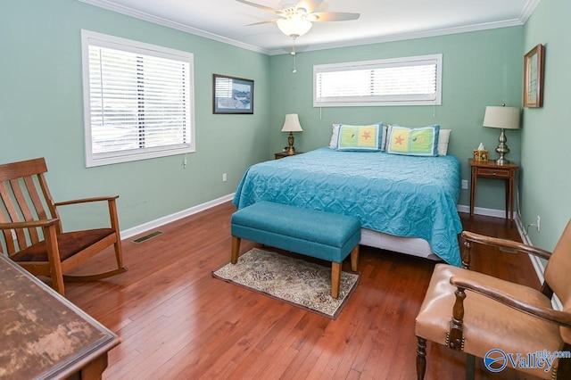 bedroom with visible vents, crown molding, ceiling fan, baseboards, and hardwood / wood-style flooring