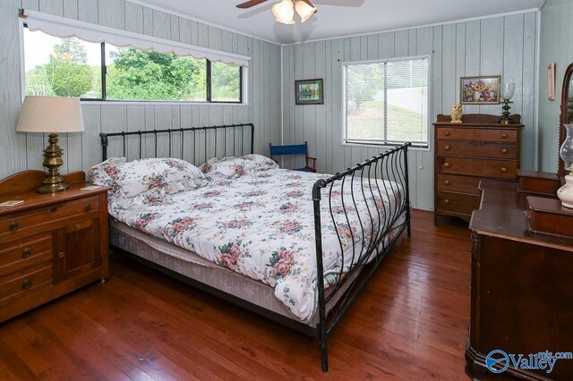 bedroom featuring ornamental molding, ceiling fan, wooden walls, and dark hardwood / wood-style flooring