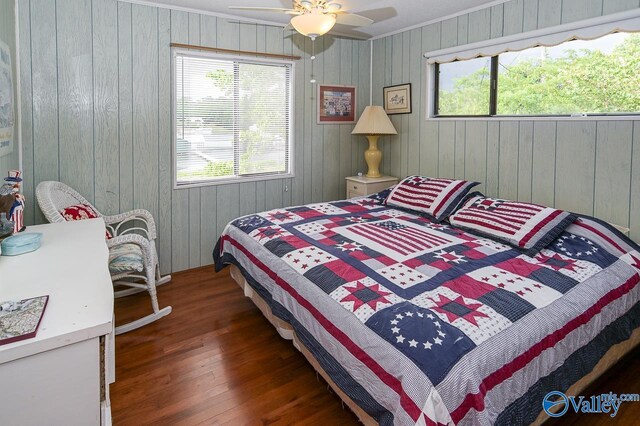 bedroom featuring dark hardwood / wood-style flooring, multiple windows, wood walls, and ceiling fan