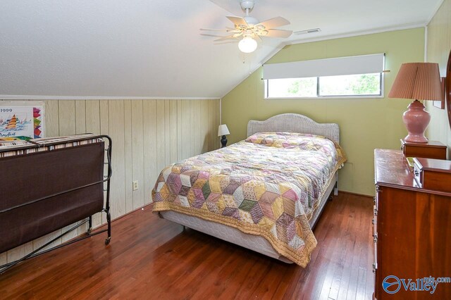 bedroom with lofted ceiling, wood walls, dark wood-type flooring, and ceiling fan