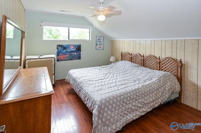 bedroom with wood walls, vaulted ceiling, ceiling fan, and dark hardwood / wood-style flooring