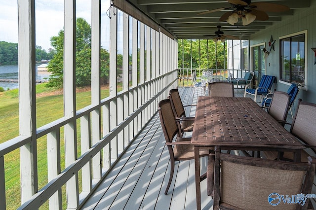 wooden deck featuring outdoor dining space, a lawn, a ceiling fan, and a water view