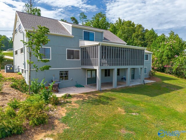 rear view of property featuring a yard, a patio, and a sunroom