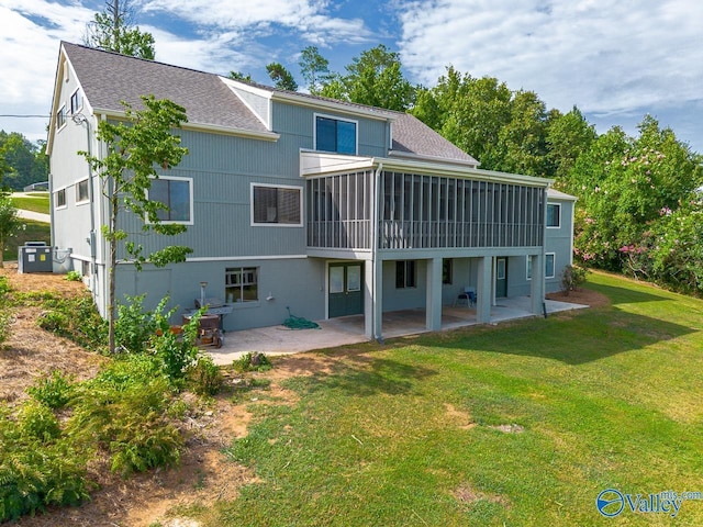 back of house featuring a sunroom, a lawn, a shingled roof, and a patio area