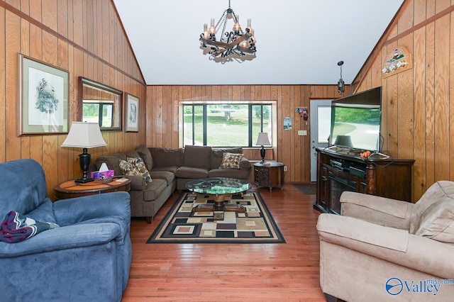 living room with a notable chandelier, wood finished floors, wood walls, and high vaulted ceiling