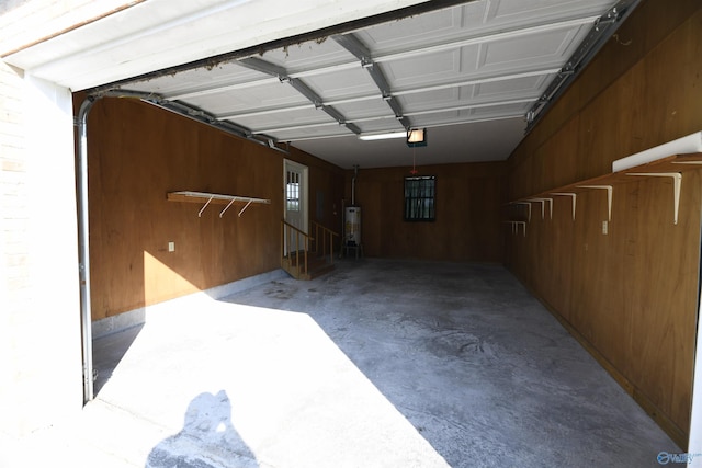 garage featuring a garage door opener, water heater, and wood walls