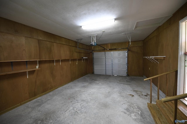 garage with a garage door opener and wood walls