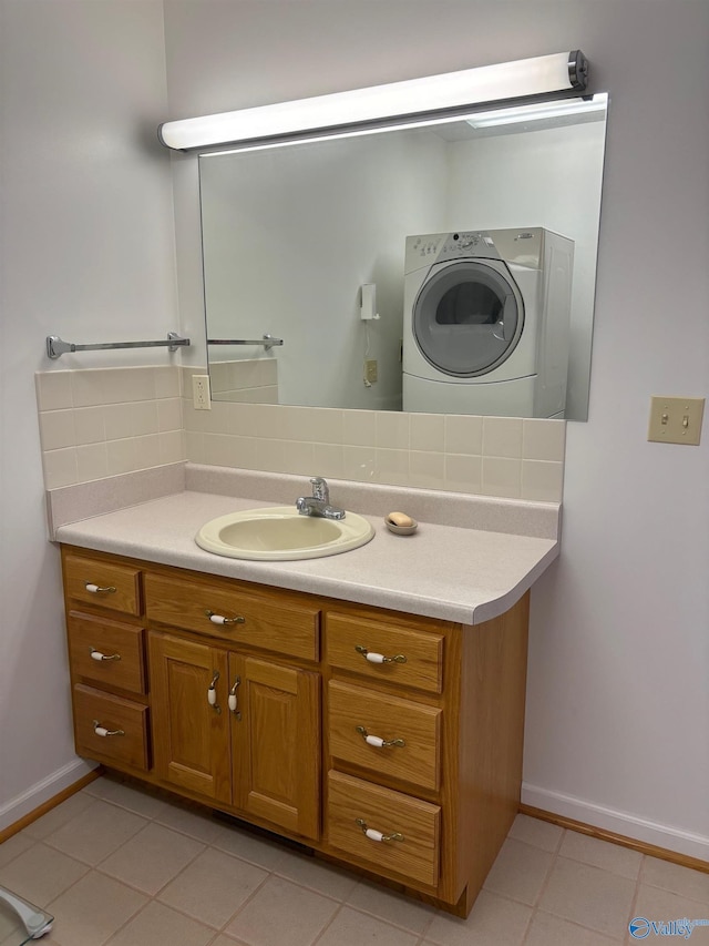 bathroom featuring washer / clothes dryer, vanity, tile patterned floors, and decorative backsplash