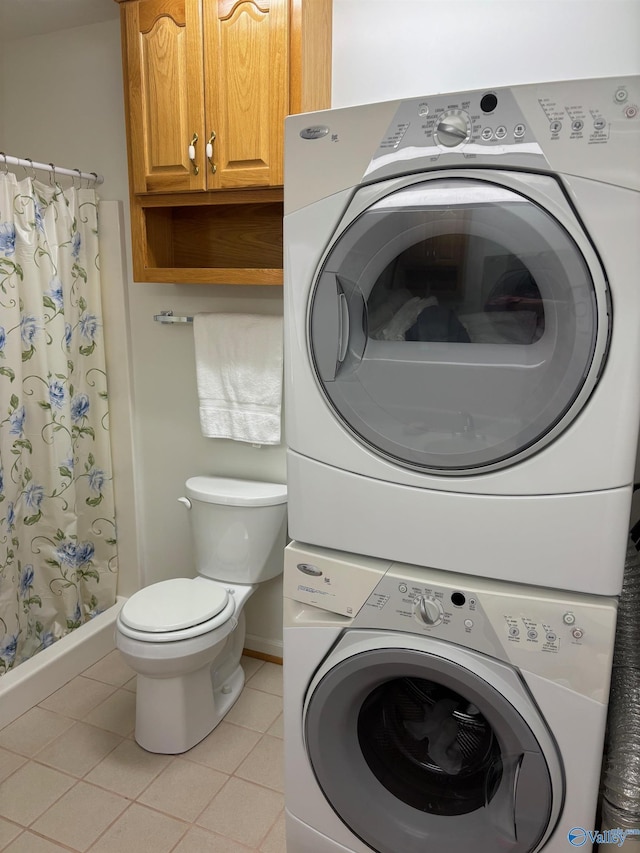 laundry area with stacked washing maching and dryer and light tile patterned flooring