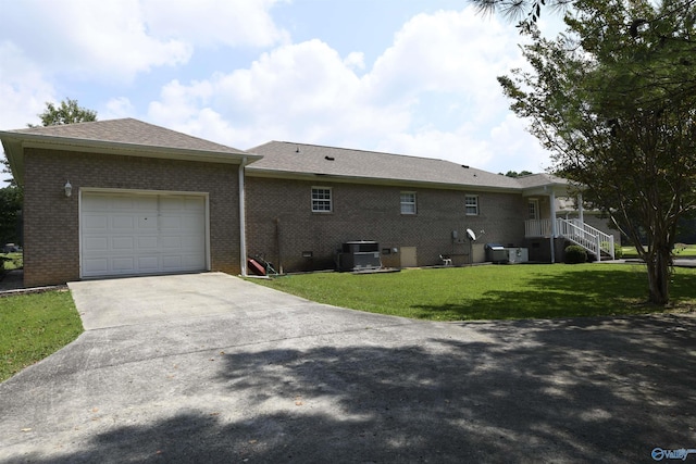 view of side of property featuring a yard, a garage, and central AC unit