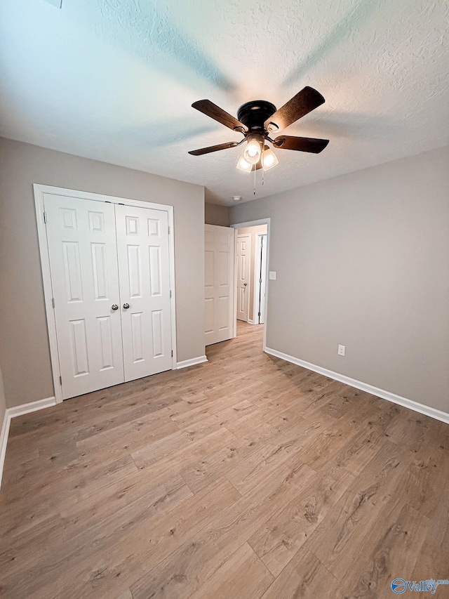 918 Wilson Ave, Gadsden, AL 35903 - unfurnished bedroom with baseboards, light wood-type flooring, a closet, a ceiling fan, and a textured ceiling