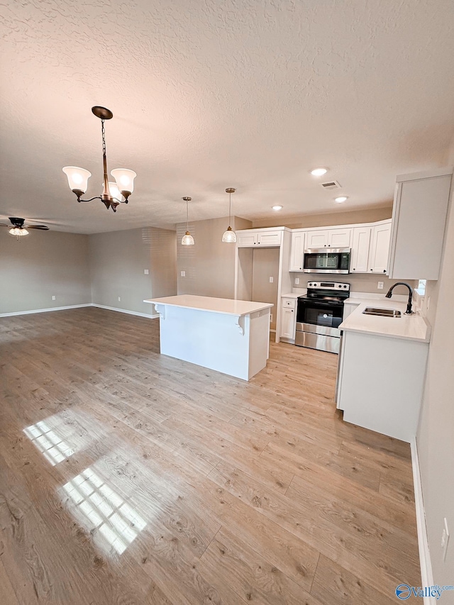 918 Wilson Ave, Gadsden, AL 35903 - kitchen with stainless steel appliances, a sink, a textured ceiling, open floor plan, and light wood-style flooring