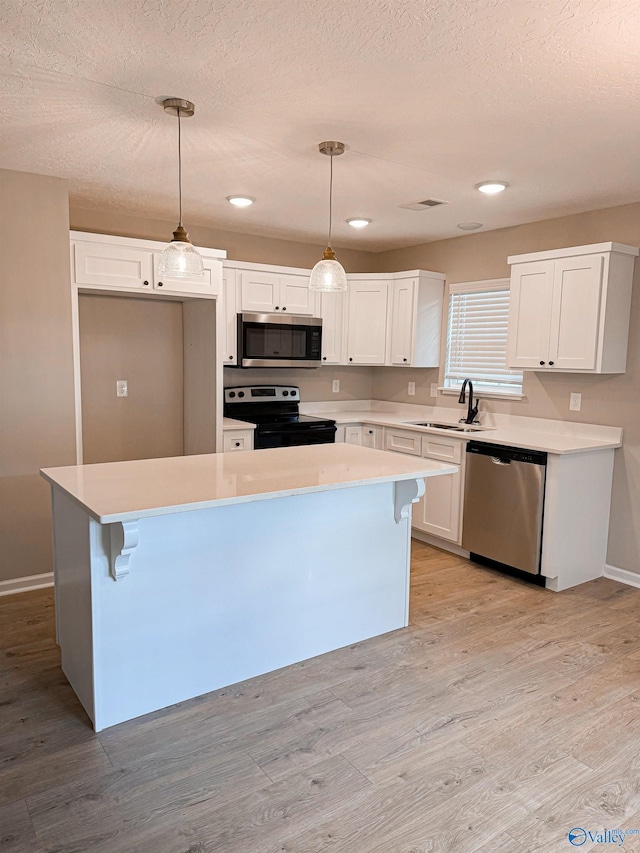 918 Wilson Ave, Gadsden, AL 35903 - kitchen with stainless steel appliances, white cabinetry, a sink, baseboards, and a kitchen island