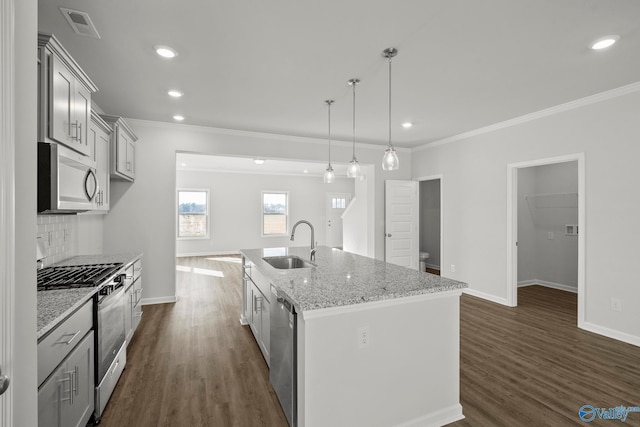 kitchen featuring pendant lighting, appliances with stainless steel finishes, sink, light stone countertops, and a center island with sink