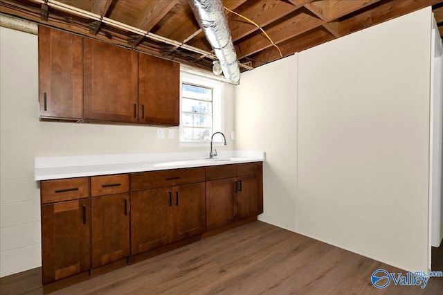 kitchen with a sink, light countertops, and wood finished floors